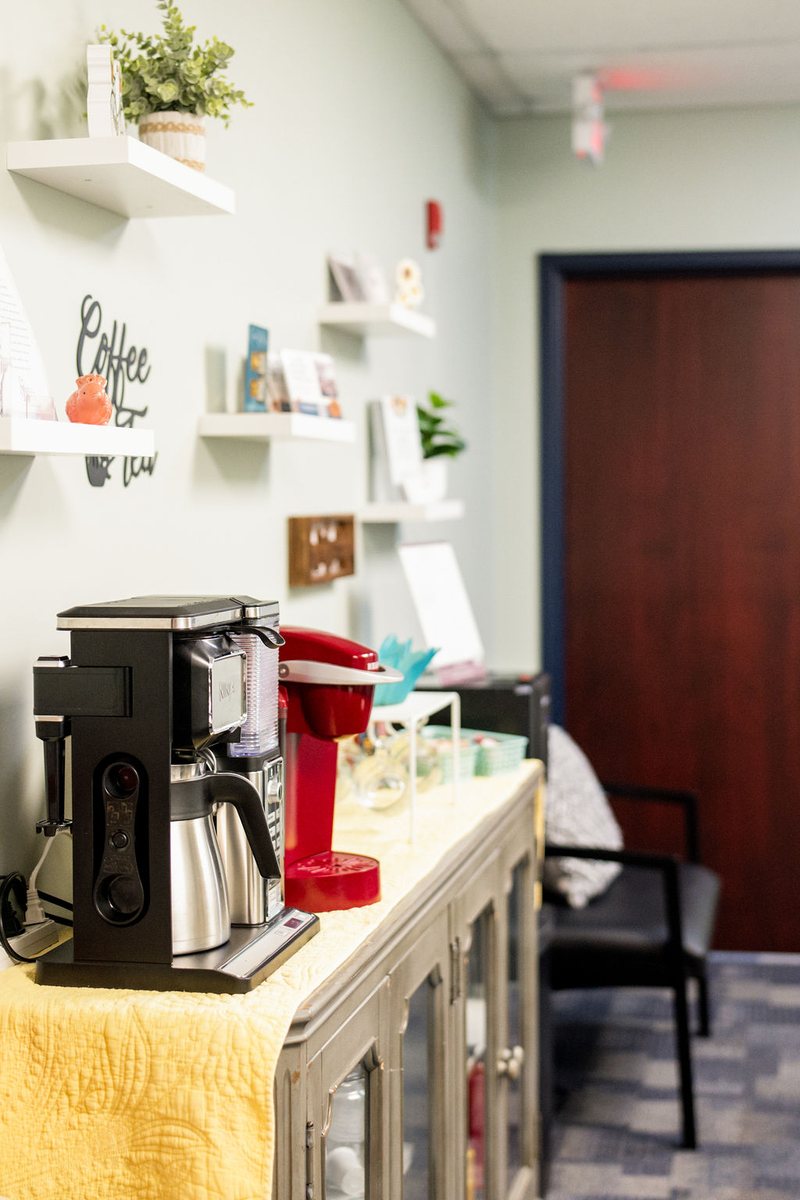 The coffee and tea bar at the Balanced Nutrition Therapy office, with shelves, plants and a coffee maker